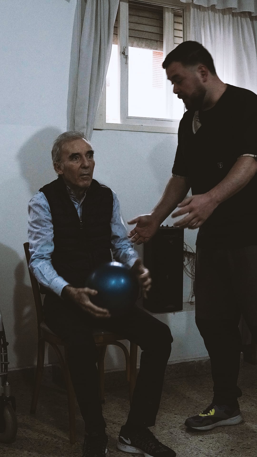 Kinesiólogo trabajando con un residente que sostiene una pelota